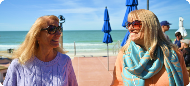 ALT Tag: Teri, a real REBLOZYL patient, and sister Sheri relaxing on the beach with the ocean behind them.