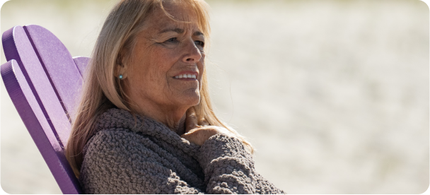 Teri, a Reblozyl patient sitting in a chair by the beach